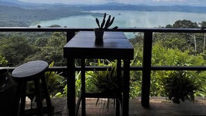 A terrace with a table and chairs, overlooking a scenic landscape with mountains and a body of water. - Bistro La Petite (San Francisco Chinameca)