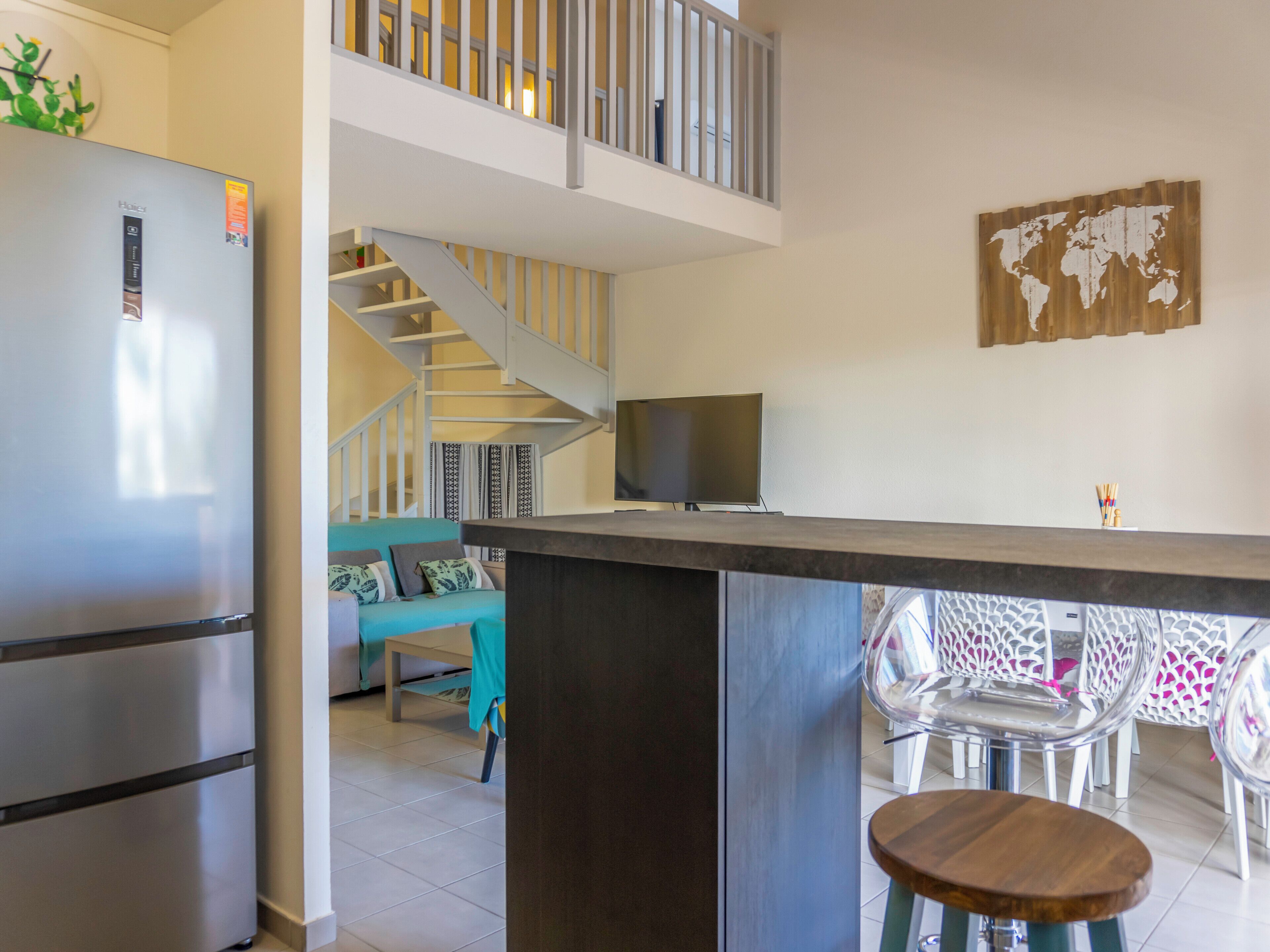 A modern kitchen with a built-in refrigerator, a dining area with a bar counter, and a staircase leading to an upper level.