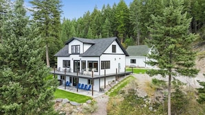 Une maison à deux étages dotée d’un balcon, entourée d’une forêt dense.