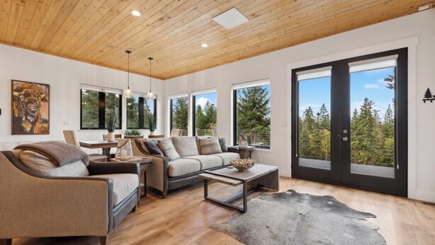 Un salon moderne avec un plafond en bois, de grandes fenêtres et une vue sur les arbres.