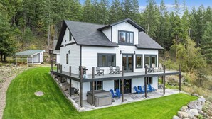 Une maison à deux étages dotée d’une terrasse couverte et d’un espace salon extérieur.