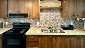 A kitchen with wooden cabinets, a granite countertop, a stove, and a sink. - The Rustic Hideaway  A Country Experience Horseback Riding and Fishing  (Cantonment)