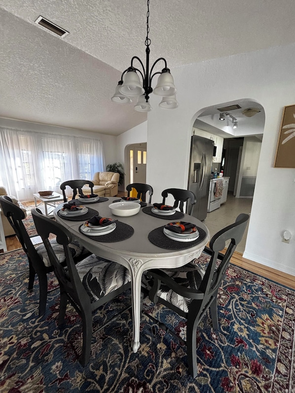 Un coin repas avec une table ronde, des chaises noires et un lustre.