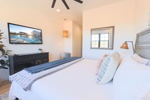 Een slaapkamer met een bed, een dressoir, een raam en een schilderij aan de muur.