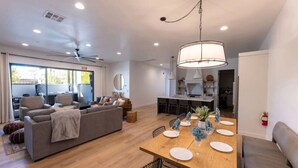 Un salon moderne avec un canapé, une table à manger pour quatre personnes et une cuisine en arrière-plan.