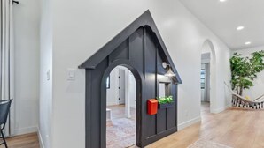 A modern interior with a dark wooden archway leading to a room, a staircase with a hammock, and a potted plant. - Desert Haven Retreat Hot Tub Fire Pit Near Zion (Hurricane)