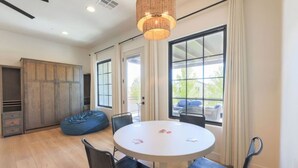 A modern room with a round table, chairs, a bean bag, a large window, and a ceiling light fixture. - Desert Haven Retreat Hot Tub Fire Pit Near Zion (Hurricane)
