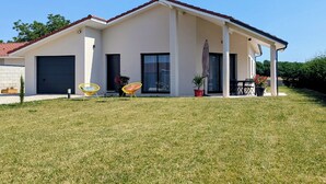 Una casa moderna de dos pisos con un porche cubierto, garaje y césped bien cuidado.