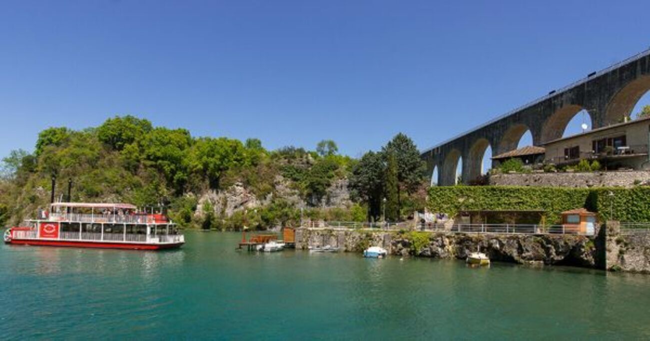 Une rivière avec un bateau, un pont et un bâtiment doté d’arcades.