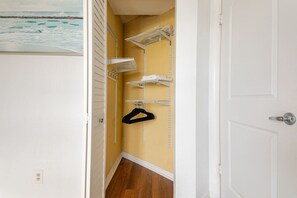 Um corredor com uma porta branca, uma parede amarela e um armário branco com prateleiras.