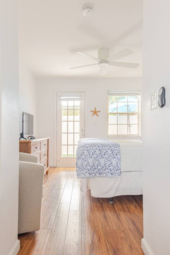 Un dormitorio con cama, ventilador de techo, decoración de estrella de mar y ventana con vistas al exterior.