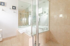 Un baño con cabina de ducha de vidrio, lavamanos doble y un espejo grande.