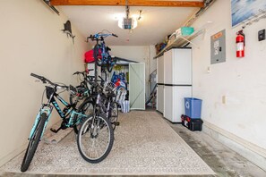 Un pasillo estrecho con bicicletas estacionadas a la izquierda, un extintor a la derecha y una puerta que da a otra habitación.