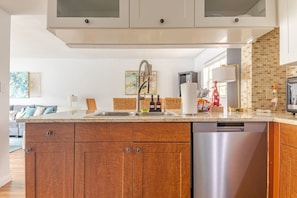 Una cocina moderna con armarios de madera, lavavajillas de acero inoxidable y salpicadero de azulejos.
