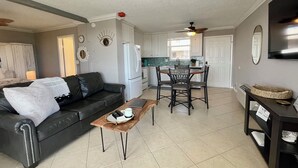 A modern living room with a black leather sofa, a wooden coffee table, and a dining area with a round table and chairs. - Penthouse condo, Gulf and Intercostal views, Bonita Beach and Tennis Club (Bonita Springs)