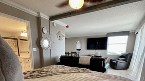A bedroom with a bed, a ceiling fan, a TV, a window, and a door leading to a bathroom. - Penthouse condo, Gulf and Intercostal views, Bonita Beach and Tennis Club (Bonita Springs)