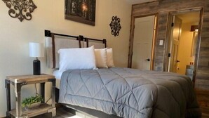 A bedroom with a bed, bedside table, lamp, and decorative wall art.