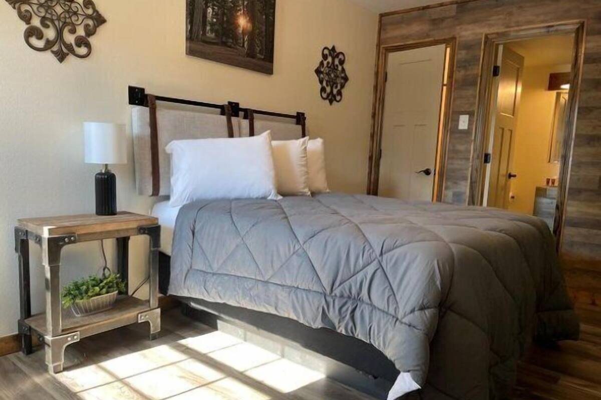A bedroom with a bed, bedside table, lamp, and decorative wall art.