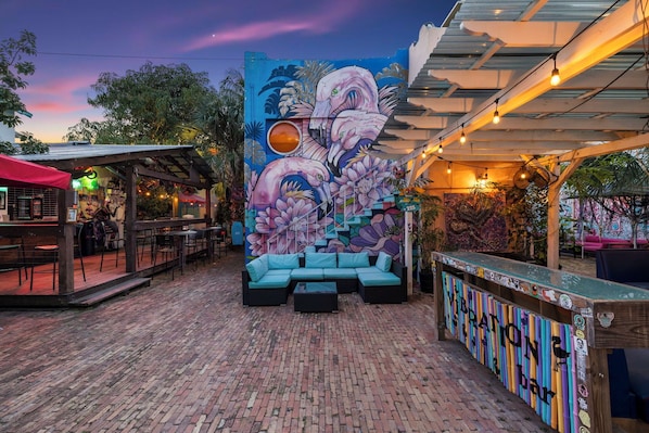 An outdoor seating area with a mural, a bar, and a covered patio.