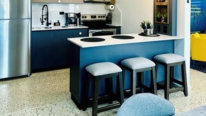 A modern kitchen with a central island, built-in appliances, and pendant lighting. - Outdoor Pool with Bar-B-Q & Television, Indoor Pool Table, Indoor Bar, PS5, Etc. (Luquillo)