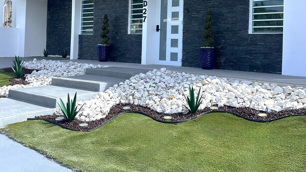 A modern house with a stone facade, a white door, and a well-maintained lawn. - Outdoor Pool with Bar-B-Q & Television, Indoor Pool Table, Indoor Bar, PS5, Etc. (Luquillo)