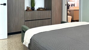 A modern bedroom with a large bed, built-in wardrobe, and a small seating area. - Outdoor Pool with Bar-B-Q & Television, Indoor Pool Table, Indoor Bar, PS5, Etc. (Luquillo)
