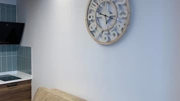Una cocina moderna con horno integrado, techo de madera y sofá beige contra la pared.