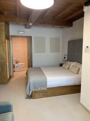Een slaapkamer met een houten bedframe, een wit matras en een nachtkastje met een lamp.