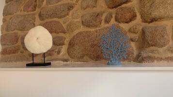 Een stenen muur met een wit schap waarop een witte ventilator en een blauwe, koraalachtige sculptuur staan.