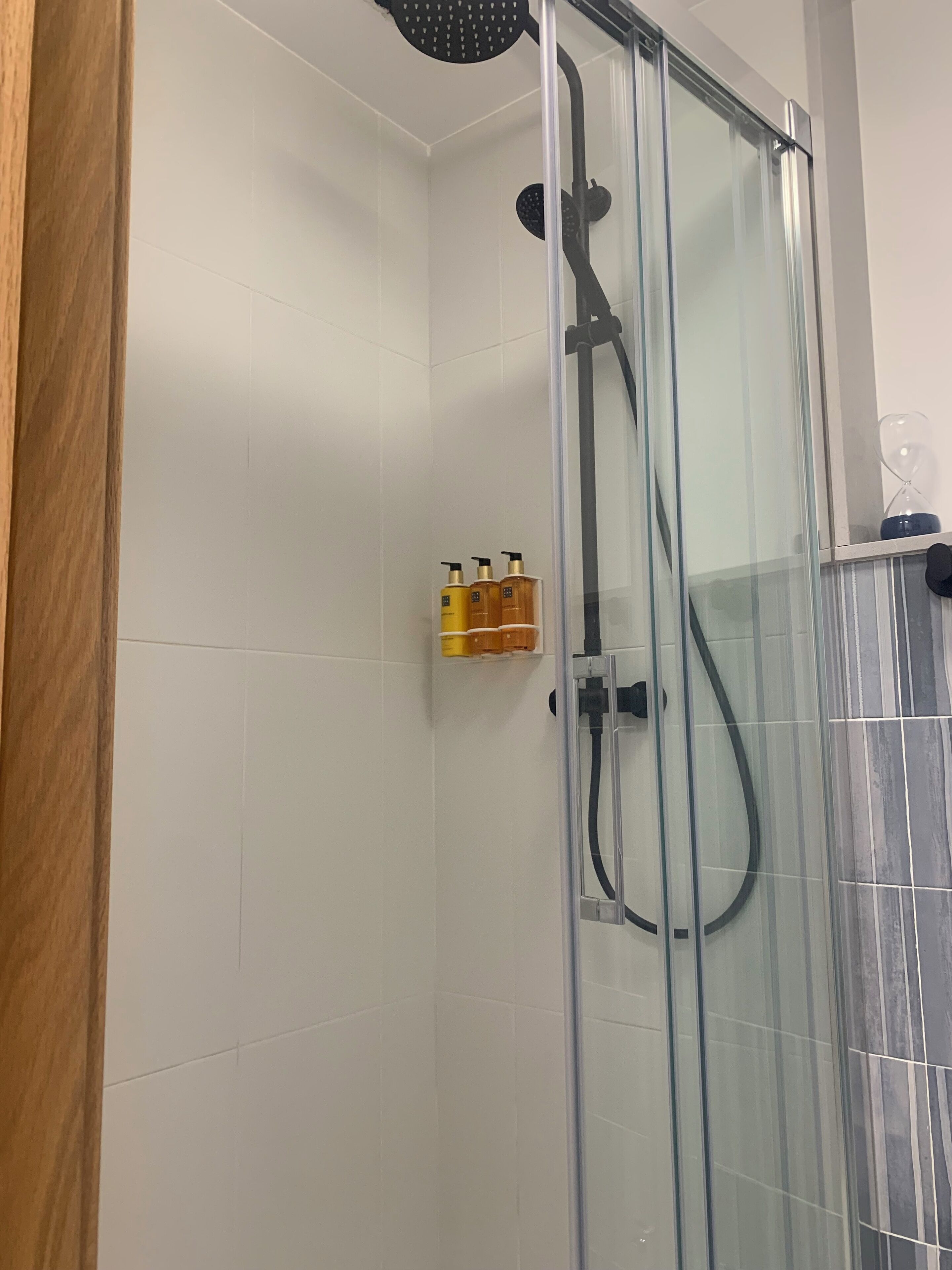 Een douche met glazen wanden, een handdouche en een wandmengkraan.