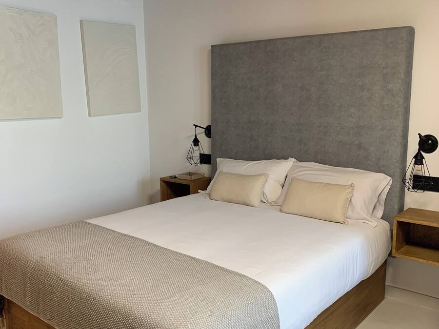 Un dormitorio con una cama grande, cabecera de madera y una mesita de noche con lámpara.