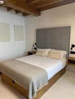 Un dormitorio con una cama grande, cabecera de madera y una mesita de noche con lámpara.