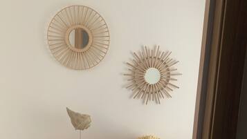 Een houten console tafel met decoratieve items, waaronder een spiegel, een beeld en een klein model zeilboot.