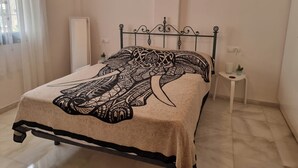 Un letto con una coperta a motivi, un comodino con una pianta e una parete con due quadri incorniciati.