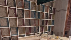 Una lavanderia piccola e funzionale con lavatrice, lavello e schienale piastrellato.