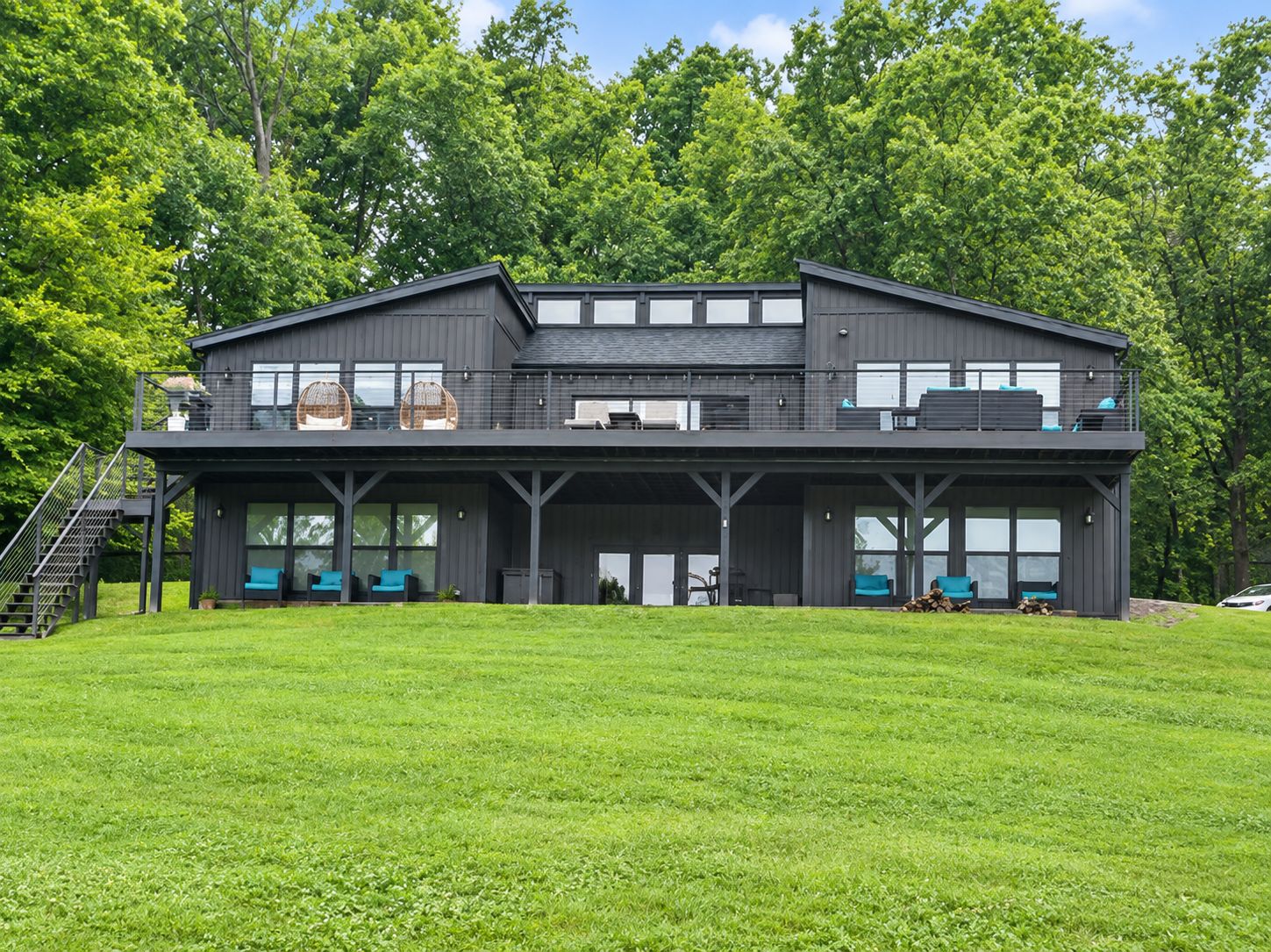 A modern two-story building with a flat roof, large windows, and a covered outdoor seating area.