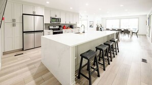 Una cocina moderna con una isla grande, electrodomésticos de acero inoxidable y taburetes de bar.