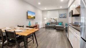 Una cocina moderna con electrodomésticos de acero inoxidable, un comedor con mesa y sillas de madera, y una sala de estar con sofá y mesa de centro.