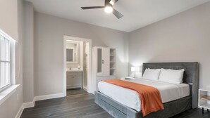 Een moderne slaapkamer met een bed, een plafondventilator, een nachtkastje en een inloopkast.