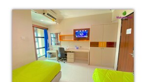 A hotel room with a bed, desk, chair, TV, wardrobe, and a window.