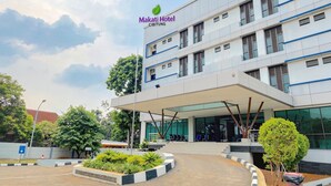 A Makati Hotel building with a modern design, featuring a covered entrance and a landscaped area with plants.