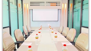 A conference room with a long table, chairs, and a projector screen.