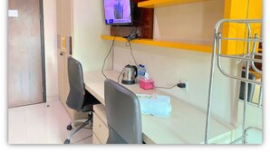 Una habitación de hotel con escritorio, silla, televisor, literas y un minibar.