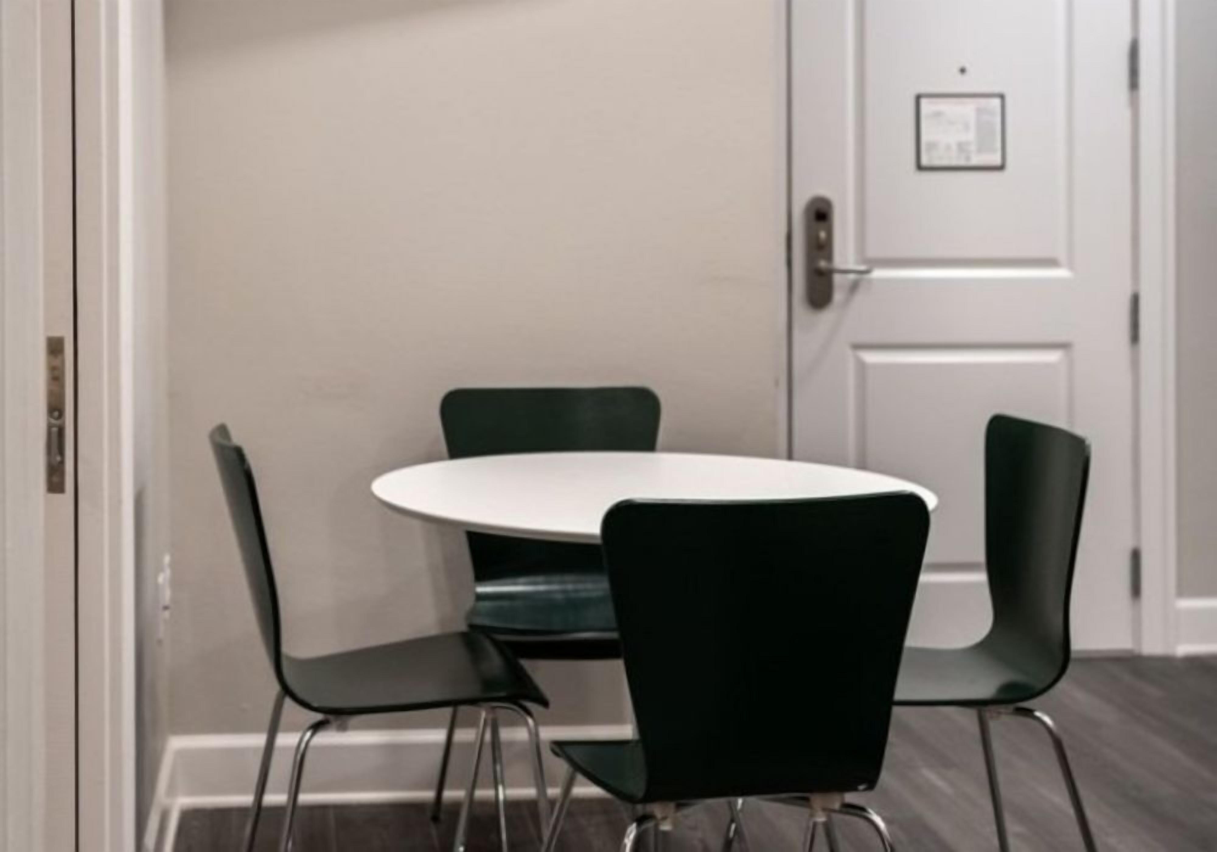 A conference room with a white table and four black chairs.