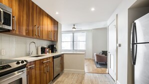 A modern kitchen with wooden cabinets, stainless steel appliances, and a view to the living area. - Frenchmen Flats Condo: 1BR Peace (New Orleans)