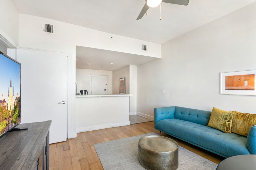 A modern living room with a blue sofa, a coffee table, and a flat-screen TV.