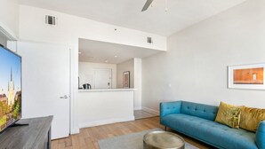Ein modernes Wohnzimmer mit einem blauen Sofa, einem Couchtisch und einem Flachbildfernseher.