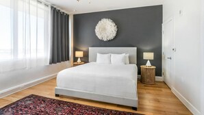 Ein Schlafzimmer mit einem großen Bett, zwei Nachttischlampen, einem Deckenventilator, einem Wanddekor und einem gemusterten Teppich.