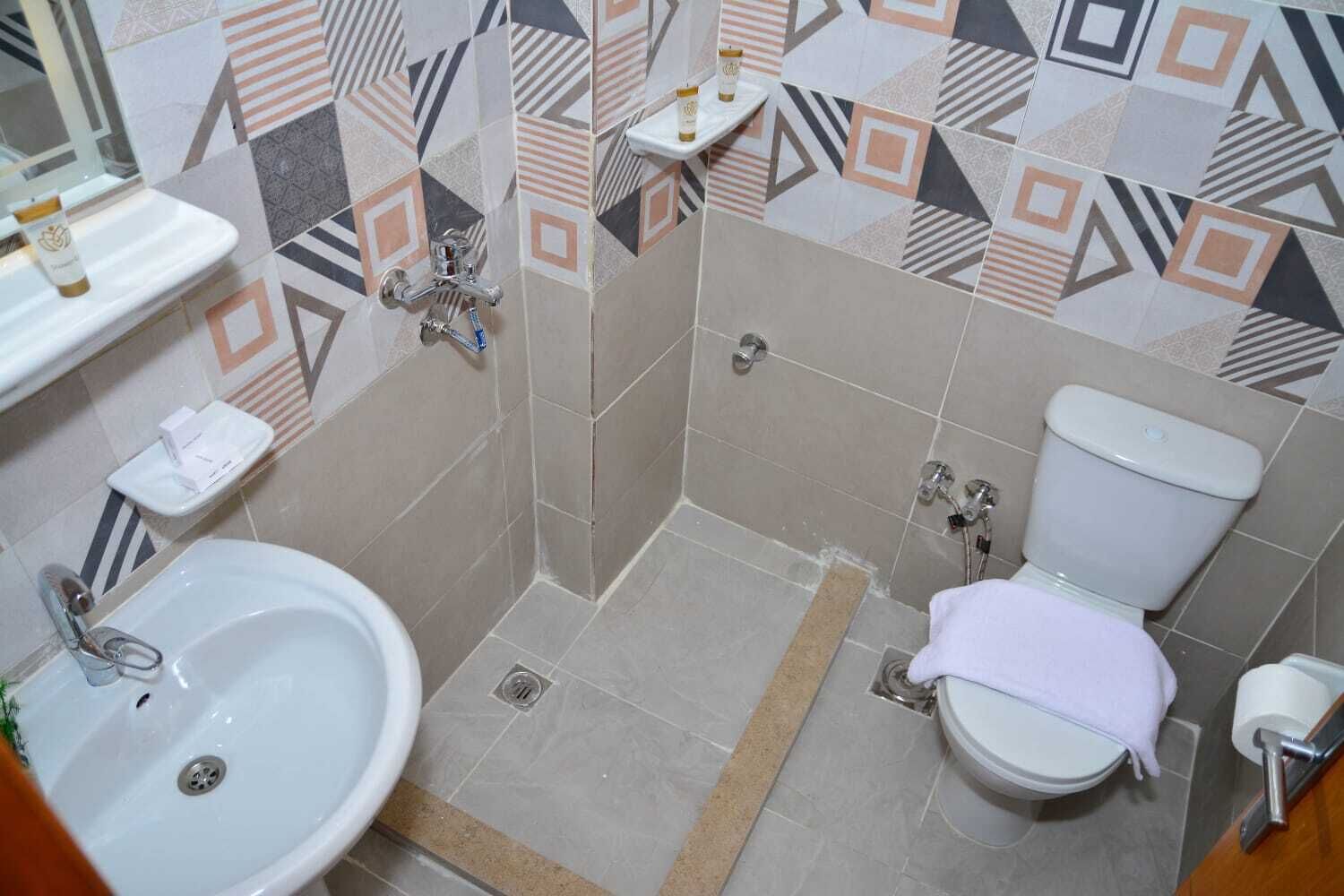 A bathroom with a sink, toilet, shower, and a towel rack.