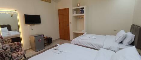 A hotel room with two beds, a desk, a chair, a TV, a wardrobe, and a chandelier.